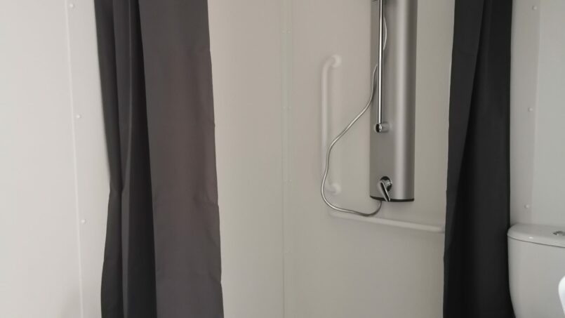 Salle de bain PMR avec douche italienne accessible fauteuil roulant, barre d'appui et siège de douche amovible