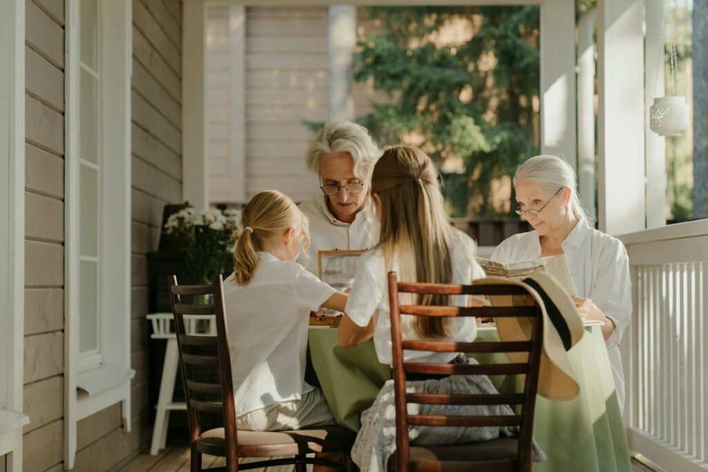 deux grands-parents et leurs deux petits-enfants partagent un déjeuner dehors autour d'une table