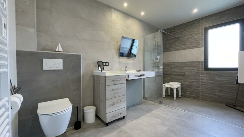 Salle de bain avec grande douche italienne et WC accessible aux personnes à mobilité réduite (PMR) en fauteuil roulant