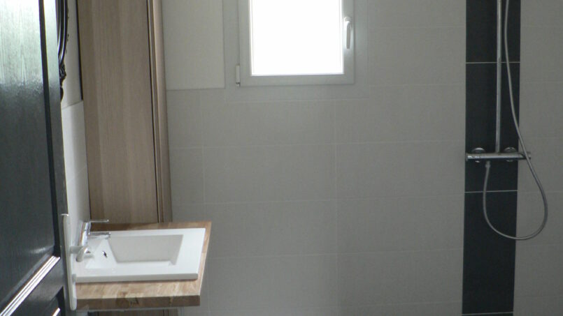 Salle de bain douche italienne avec barres d'appui et lavabo sans meuble dessous pour les personnes à mobilité réduite en fauteuil roulant