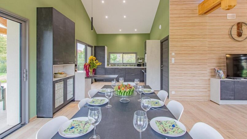 Salle à manger colorée avec assiettes, verres et couverts dressés et une cuisine