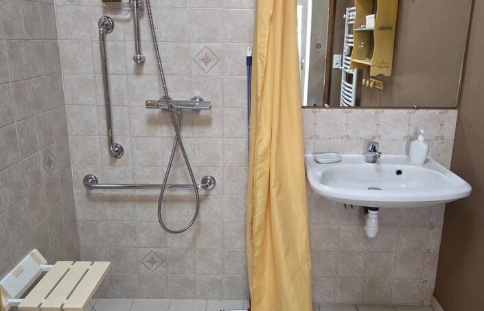 Salle de bain PMR avec siège douche intégré ou fauteuil douche amovible pour les personnes à mobilité réduite en fauteuil roulant