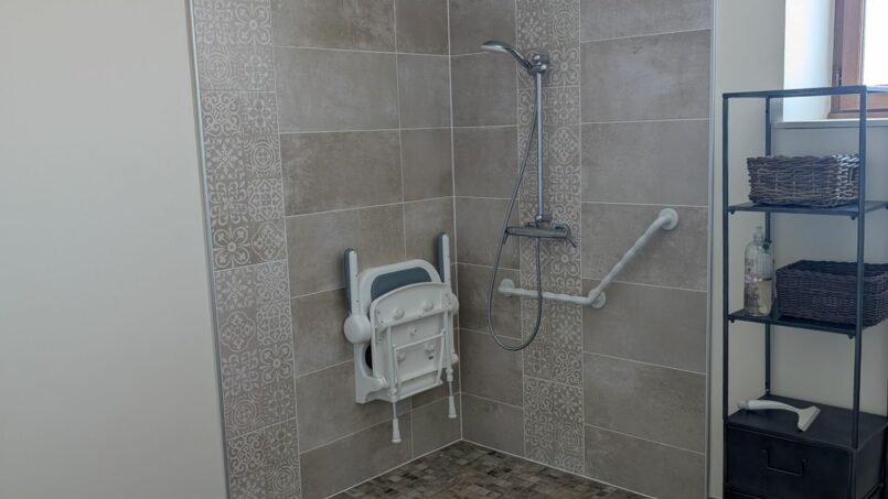 Douche avec barre d'appui et siège douche encastré pour les personnes à mobilité réduite en fauteuil roulant