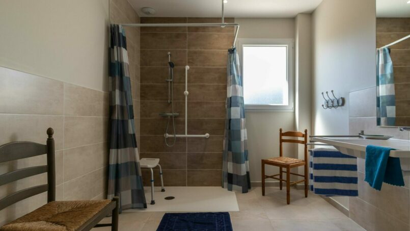 grande salle de bain PMR accessible aux fauteuils roulants avec barre d'appui